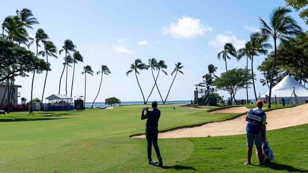 Mark Hubbard hits a shot with the iconic Waialae Country Club tree-form "W" in the background at the 2023 Sony Open in Hawaii.